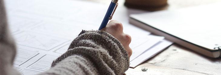 6 Tipps, die dein Bewerbungsschreiben einzigartig machen Bewerber schreibt mit Stift auf einem Papier ein Bewerbungsschreiben